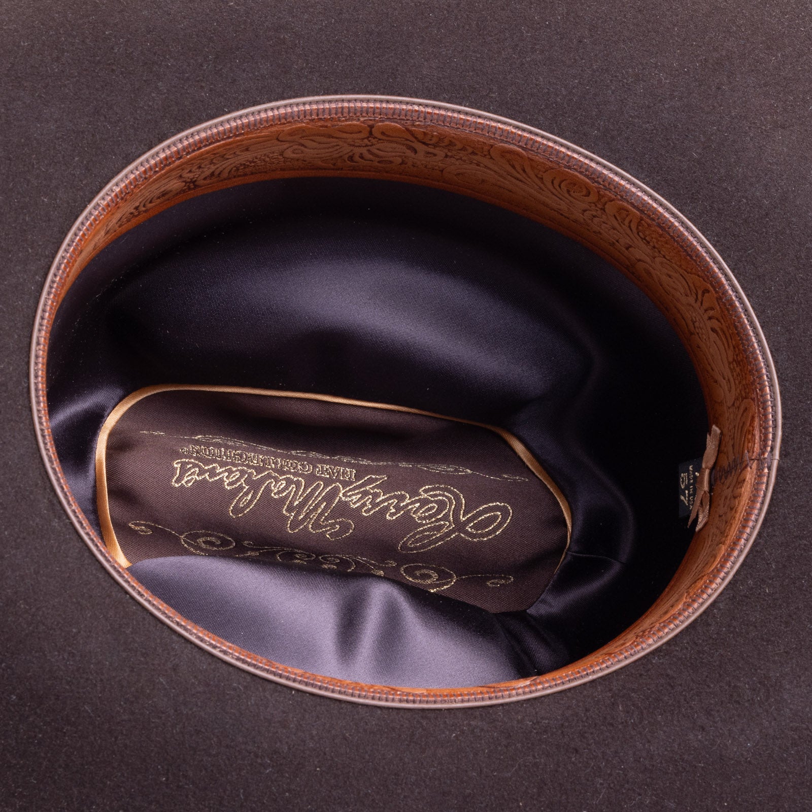 30X Opulento brown cowboy hat closeup of the underside with black interior, burnt orange trim, and brown lettering