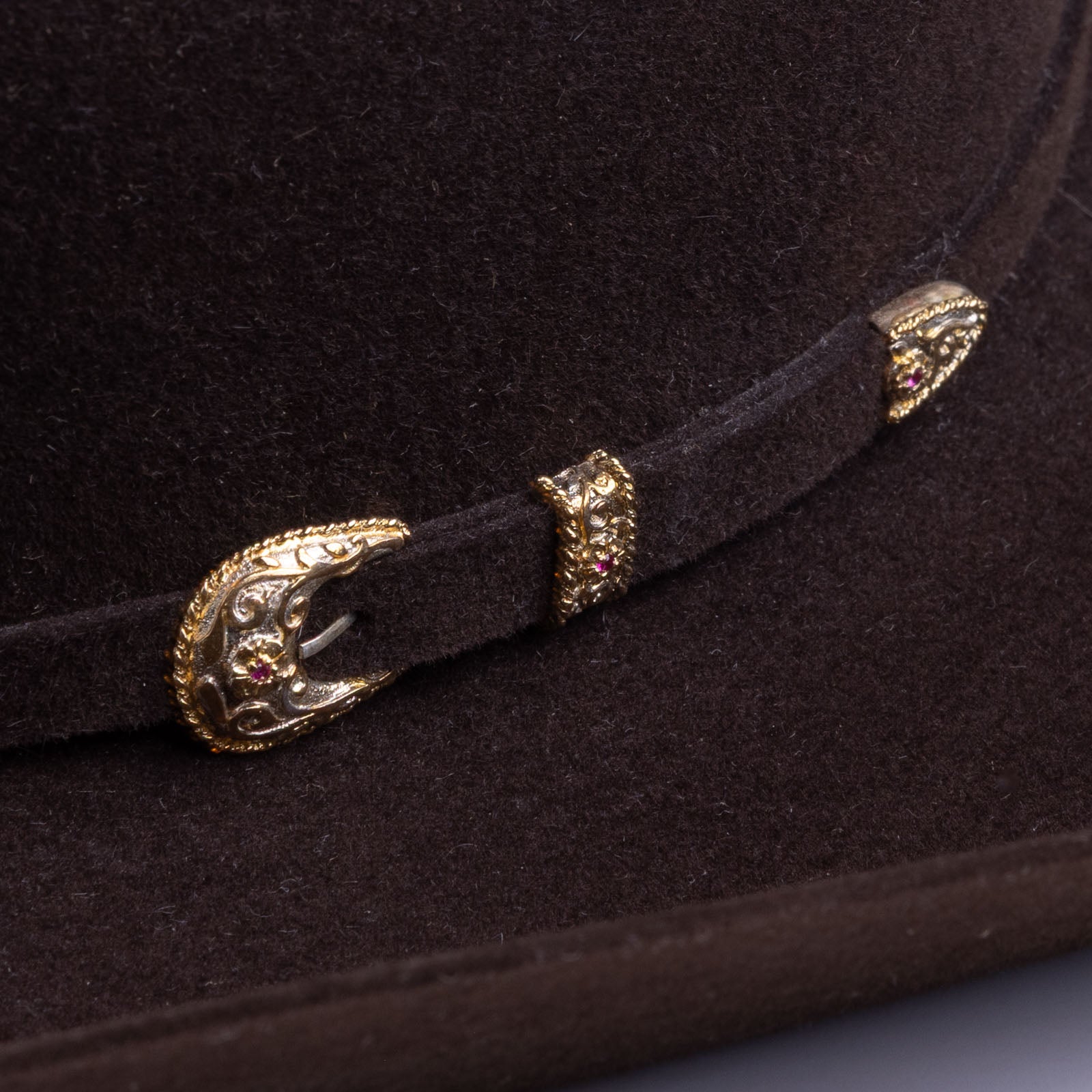 30X El Rey brown cowboy hat closeup of buckle as a gold and silver buckle with a few red gems inlaid in the middle on a brown band