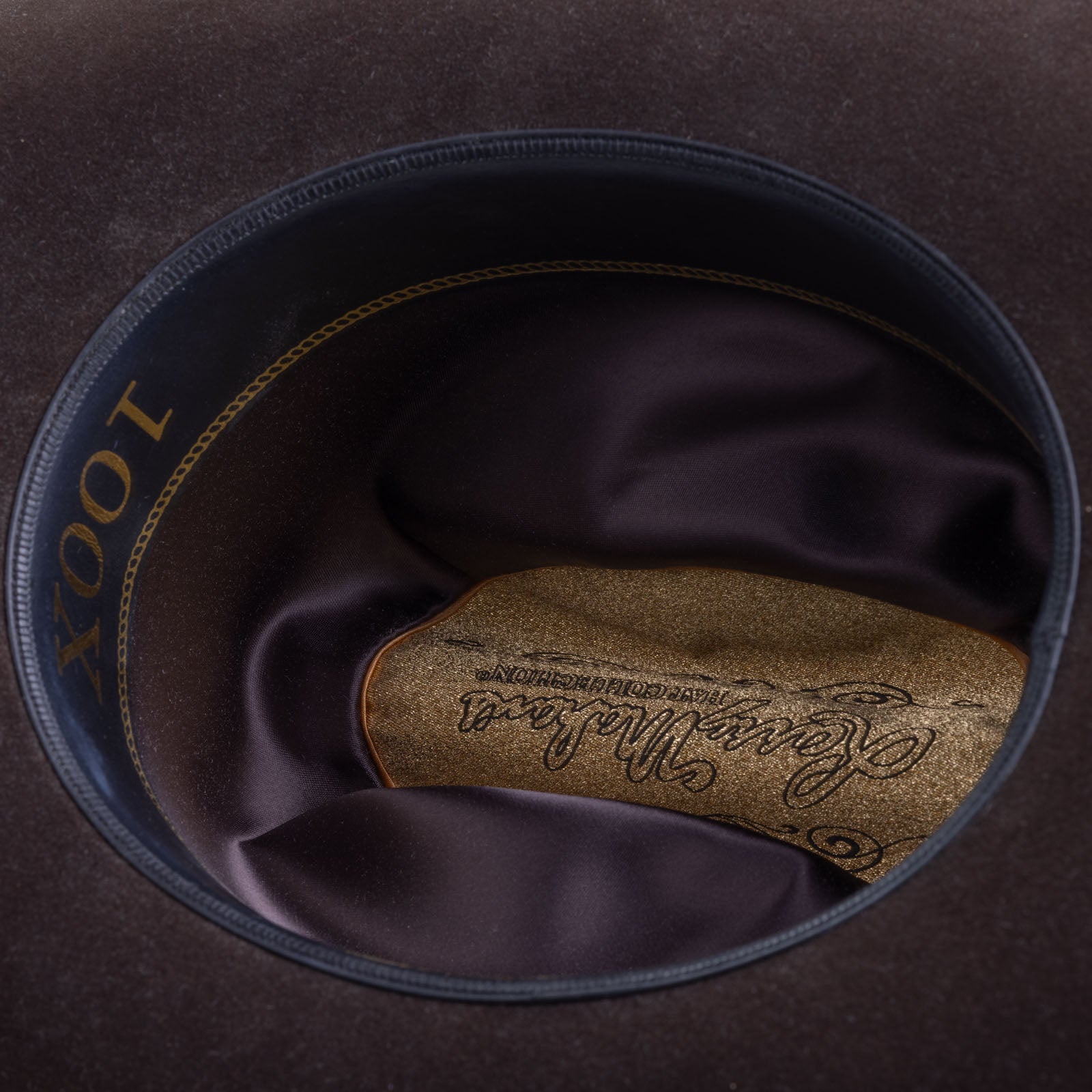 100X Independencia brown cowboy hat closeup of the underside with black interior, gold trim and lettering