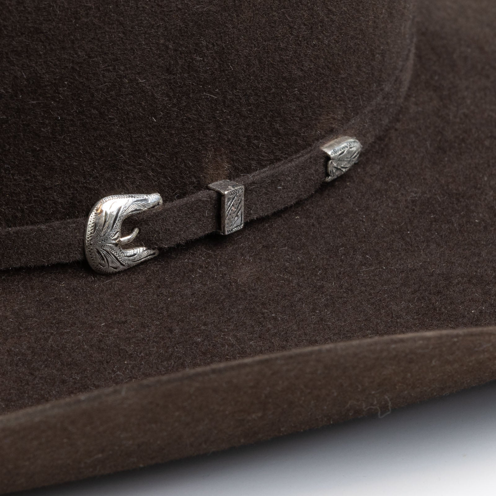 5X Fort Worth brown cowboy hat closeup of buckle in silver with small intricate etchings on a brown band