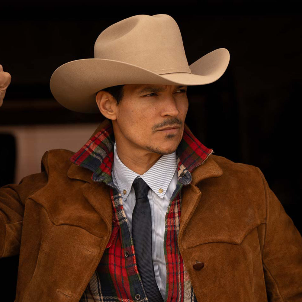 Man wearing a 6X El Oro fawn cowboy hat with brown jacket, red and blue plaid long sleeve shirt, white under shirt, and black tie