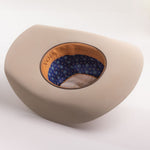 A light beige cowboy hat shown from a three-quarters angle, displaying its patterned blue and orange patterned inner crown lining