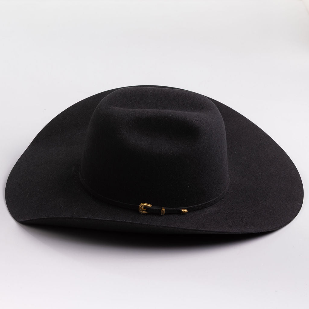 A black felt cowboy hat with a small gold buckle detail on the band, photographed on a clean light gray background