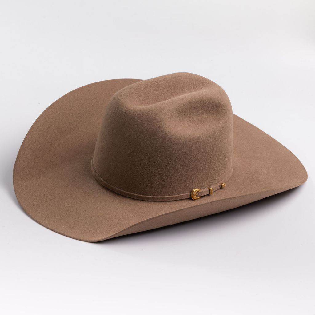 A classic felt cowboy hat in a fawn brown color, featuring a small gold-tone buckle on the band, set against a clean light gray background