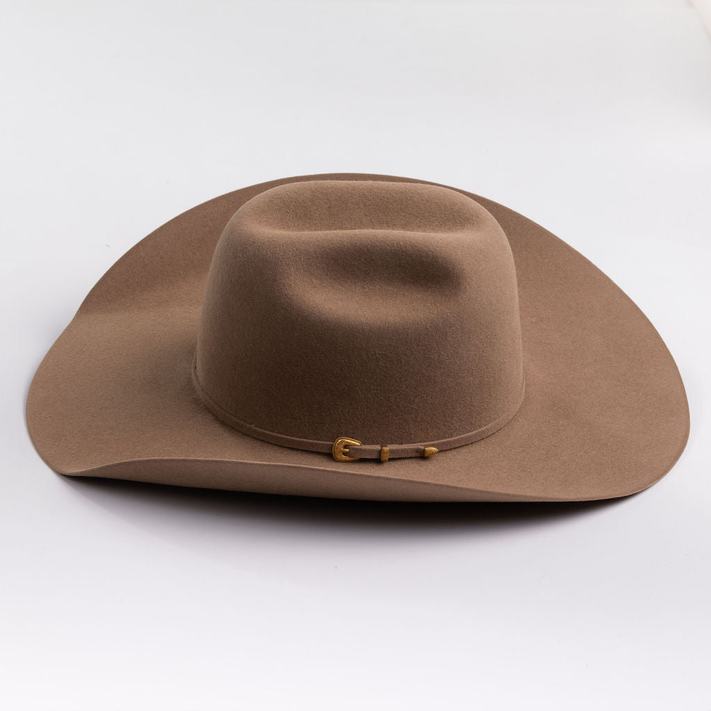 A classic felt cowboy hat in a fawn brown color, featuring a small gold-tone buckle on the band, set against a clean light gray background