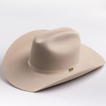 A light beige felt cowboy hat with a matching band and a small gold-toned buckle, photographed on a clean light gray background