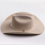 A light beige felt cowboy hat with a matching band and a small gold-toned buckle, photographed on a clean light gray background
