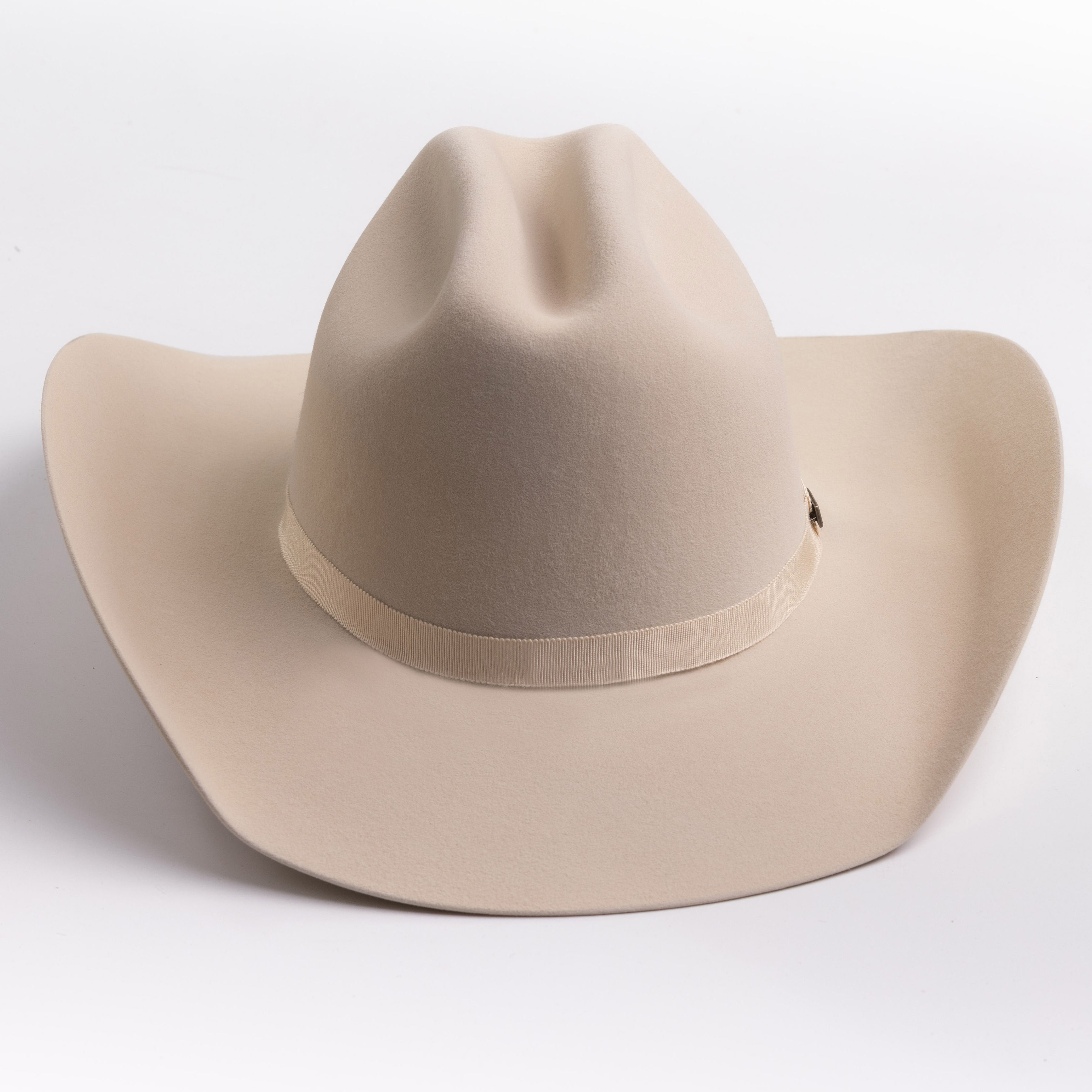 A light beige felt cowboy hat with a matching band and a small gold-toned buckle, photographed on a clean light gray background