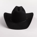 A black felt cowboy hat with a curved brim and a small gold brand plaque on the band, photographed on a light gray background