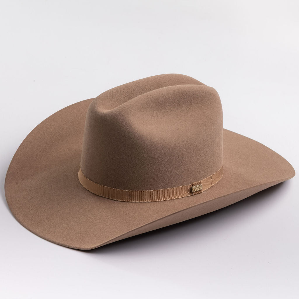 A classic felt cowboy hat in a fawn brown color, featuring a matching band with a small gold-tone metal buckle, photographed on a light gray background