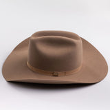 A classic felt cowboy hat in a fawn brown color, featuring a matching band with a small gold-tone metal buckle, photographed on a light gray background