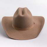 A classic felt cowboy hat in a fawn brown color, featuring a matching band with a small gold-tone metal buckle, photographed on a light gray background