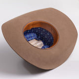 A fawn brown cowboy hat shown from a top-down angle, displaying its tan leather trim and a blue patterned fabric interior and 6X text inside
