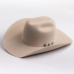 A light beige felt cowboy hat with a curved brim and a small silver buckle detail on the band, photographed on a clean light gray background