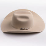 A light beige felt cowboy hat with a curved brim and a small silver buckle detail on the band, photographed on a clean light gray background