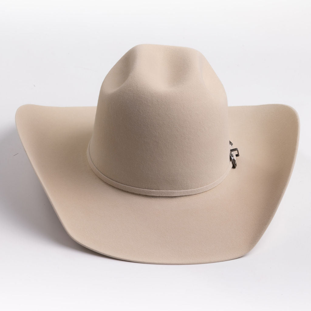 A light beige felt cowboy hat with a curved brim and a small silver buckle detail on the band, photographed on a clean light gray background