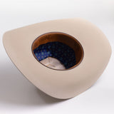 A light beige wide-brim cowboy hat shown from an overhead angle, displaying its brown leather interior band and blue patterned inner lining
