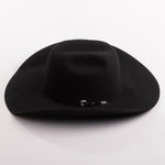 A black felt cowboy hat with a small silver decorative buckle on the band, photographed on a clean light gray background