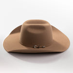 A classic felt cowboy hat in a warm tan-brown color, featuring a small silver-toned decorative buckle on the band, set against a clean light gray background
