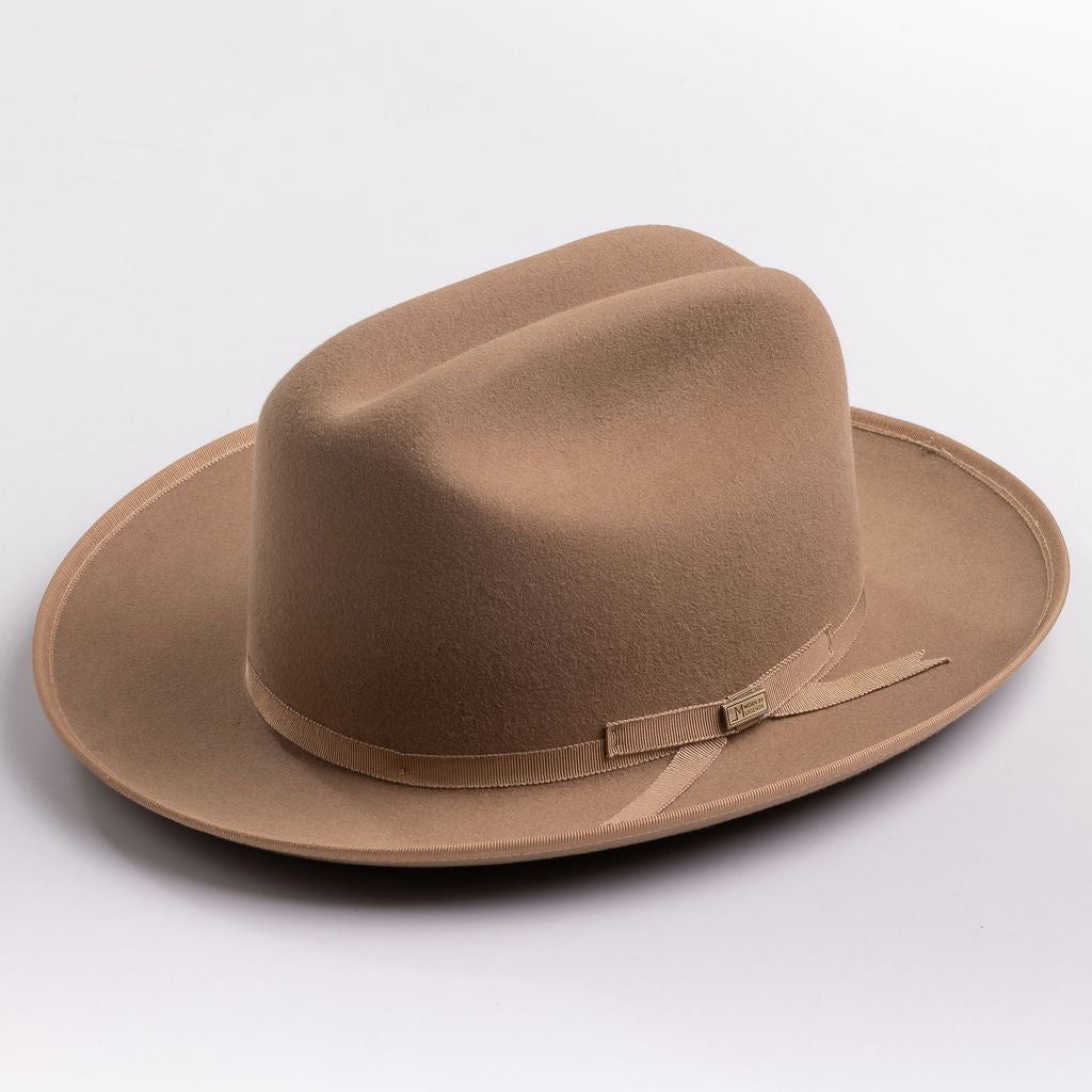 A classic felt hat in a fawn brown color, featuring a matching fabric band with a small decorative buckle, photographed on a light gray background