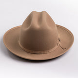 A classic felt hat in a fawn brown color, featuring a matching fabric band with a small decorative buckle, photographed on a light gray background