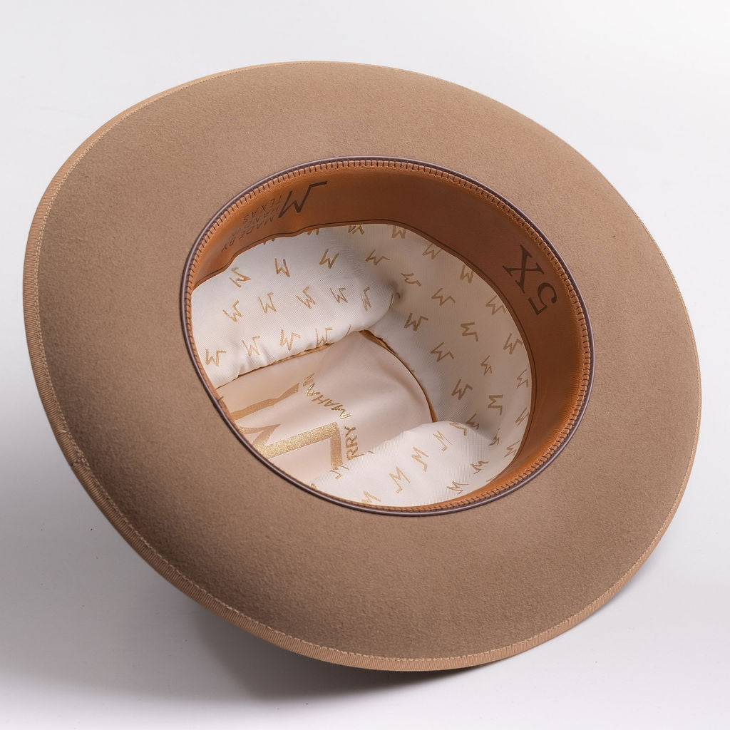 A fawn brown colored wide-brim felt hat shown from an overhead angle, displaying its cream-colored patterned interior lining and brown inner band with 5X text