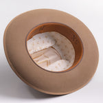 A fawn brown colored wide-brim felt hat shown from an overhead angle, displaying its cream-colored patterned interior lining and brown inner band with 5X text