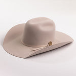 A light beige felt cowboy hat with a matching band and a small round gold-tone button, photographed on a clean light gray background