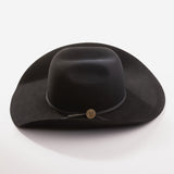 A black felt cowboy hat with a wide brim, a black ribbon band, and a small round gold button accent, photographed on a clean light gray background