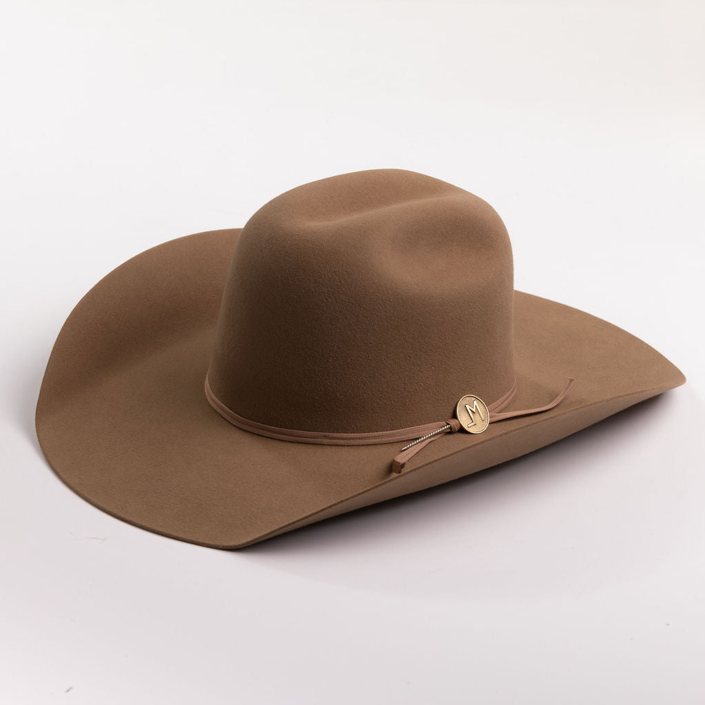 A brown felt cowboy hat with a matching band and a small gold-toned decorative button, photographed on a clean light gray background