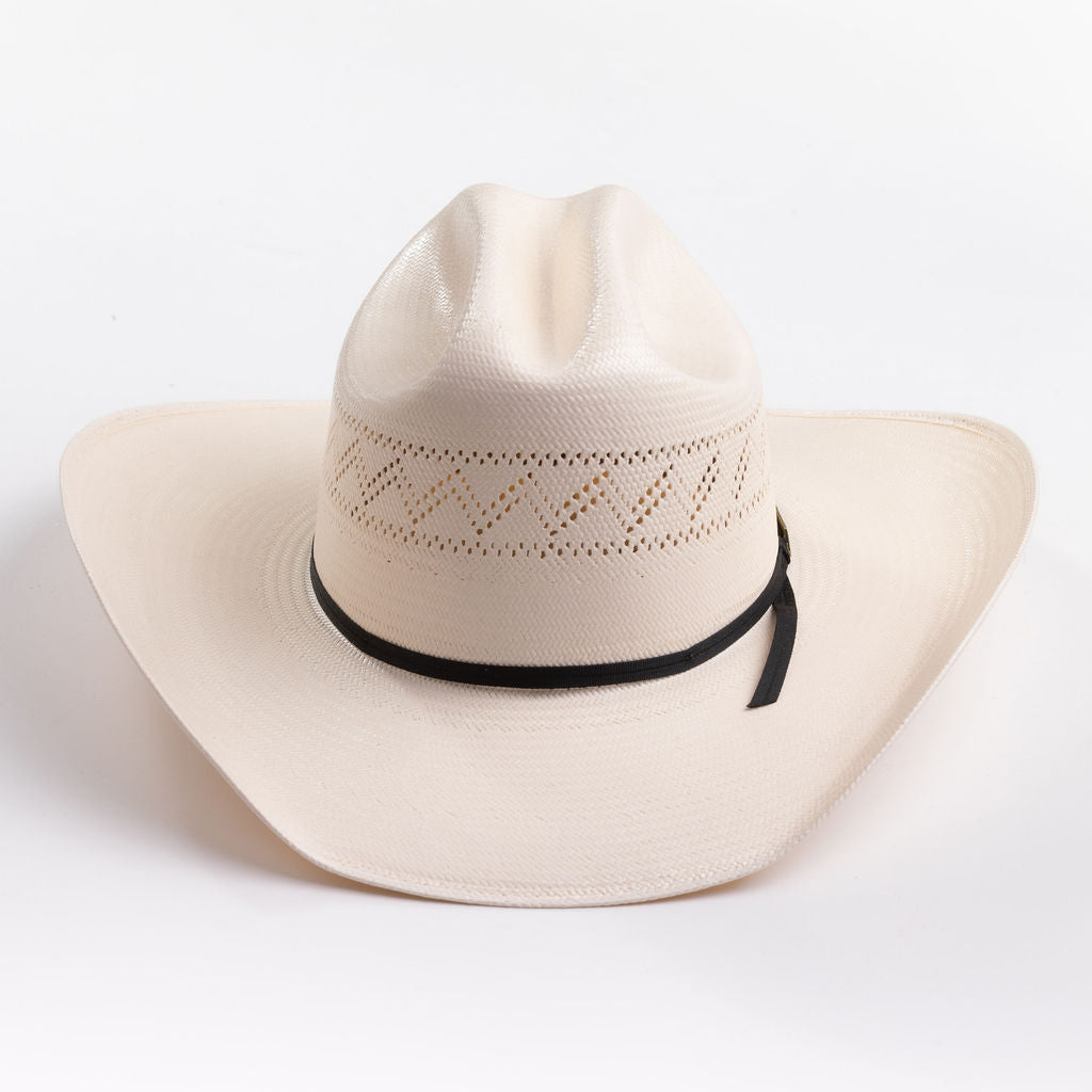 A light cream-colored woven cowboy hat with a black ribbon band and a small gold logo tag, photographed on a clean light gray background