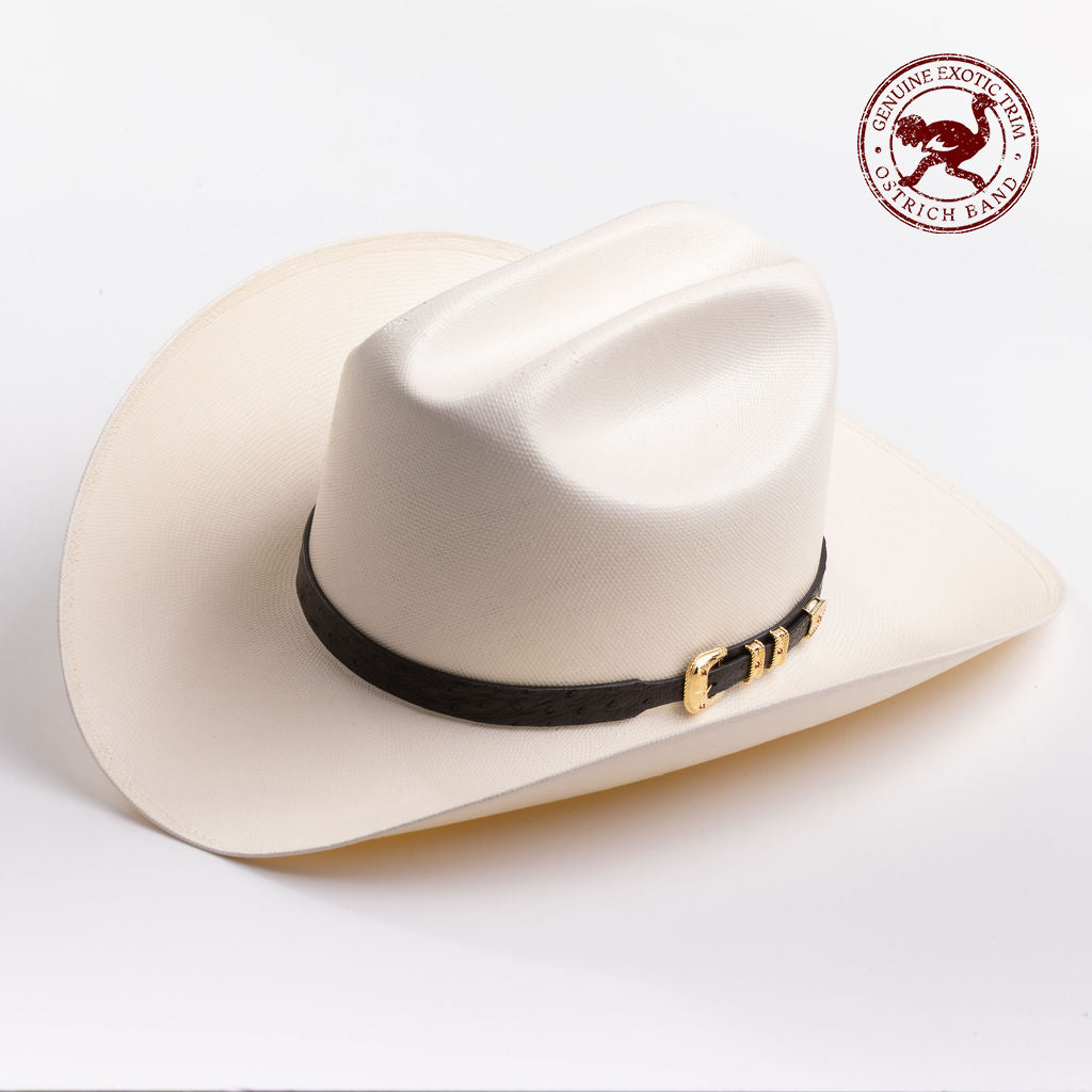 An off-white cowboy hat with a black band and gold buckle, photographed on a clean light gray background - ostrich band in red is stamped in the top right corner of the photo