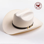 An off-white cowboy hat with a black band and gold buckle, photographed on a clean light gray background - ostrich band in red is stamped in the top right corner of the photo
