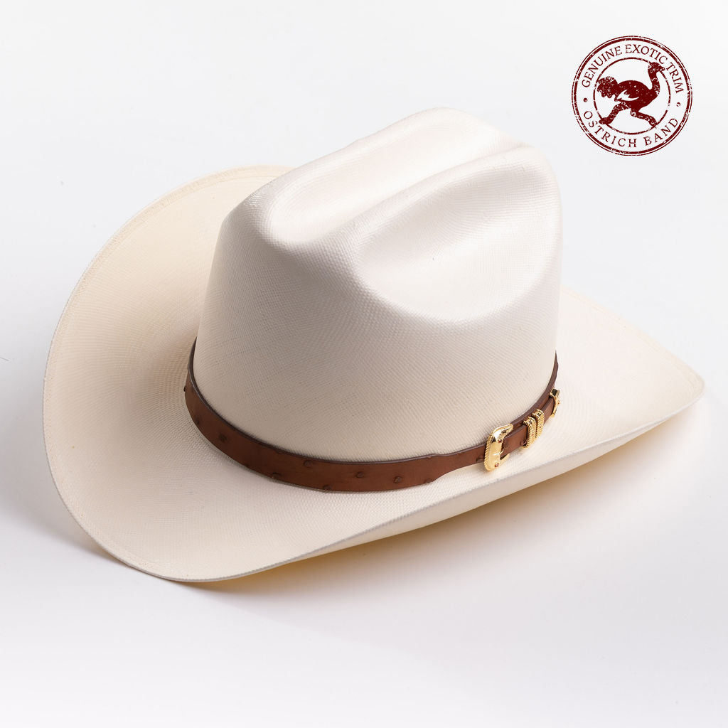 A cream-colored cowboy hat with a brown leather band and gold buckle, photographed on a clean light gray background - ostrich band in red is stamped in the top right corner of the photo