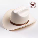 A cream-colored cowboy hat with a brown leather band and gold buckle, photographed on a clean light gray background - ostrich band in red is stamped in the top right corner of the photo