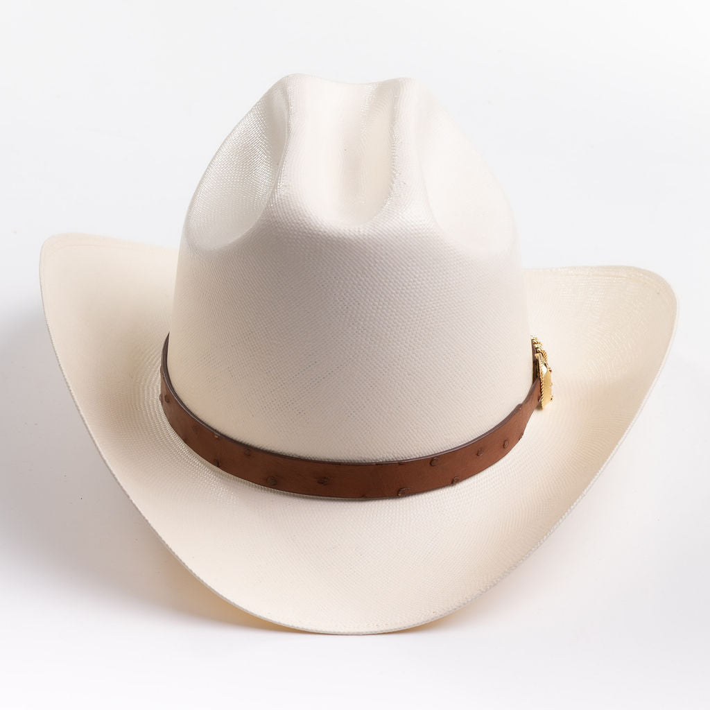 A cream-colored cowboy hat with a brown leather band and gold buckle, photographed on a clean light gray background