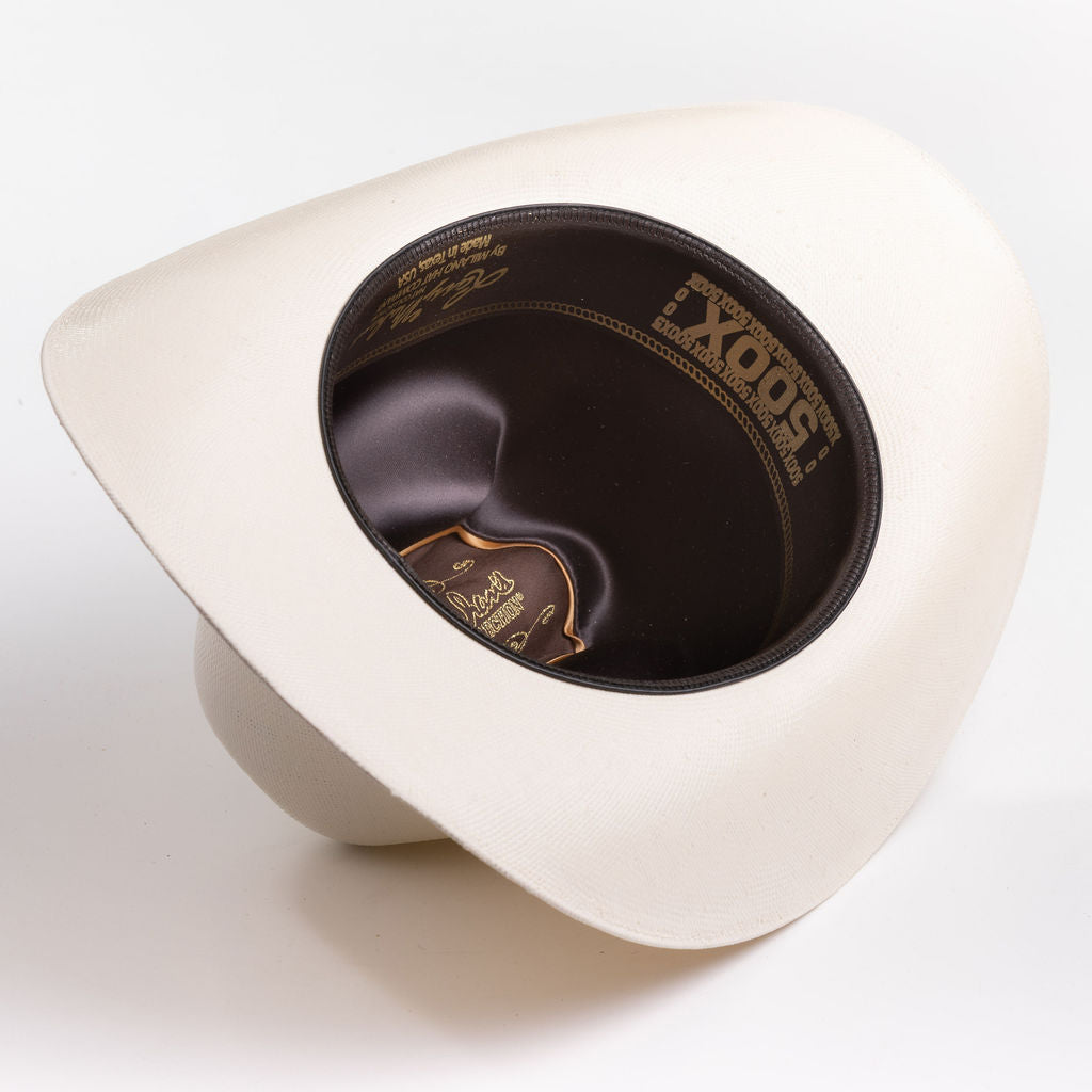 An off-white cowboy hat shown from an angled top-down view, displaying a dark brown interior with gold-embossed branding