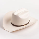 An off-white colored cowboy hat with a dark brown band and gold buckle, photographed on a clean white background
