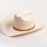 An off-white cowboy hat with a textured finish and a brown patterned band around the crown, shown against a plain white background