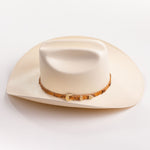 An off-white cowboy hat with a textured finish and a brown patterned band around the crown, shown against a plain white background
