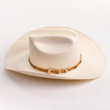 An off-white cowboy hat with a textured finish and a brown patterned band around the crown, shown against a plain white background