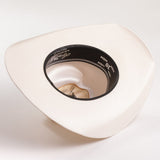 An off-white colored cowboy hat photographed from a top-down angle, showing the black inner band with white text