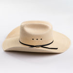 A light beige woven straw cowboy hat with a black ribbon band and a small silver buckle, photographed on a clean white background