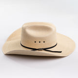 A light beige woven straw cowboy hat with a black ribbon band and a small silver buckle, photographed on a clean white background