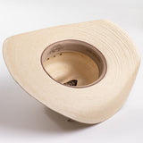 A light beige woven straw cowboy hat with a black ribbon band and a small silver buckle, photographed on a clean white background