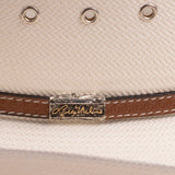 Close-up of an off-white cowboy hat featuring silver-tone eyelets and a brown leather band accented by a silver-toned metal logo plaque reading as 'Larry Mahan's'