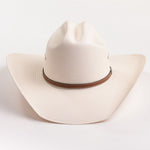 An off-white woven cowboy hat with a brown band around the crown, photographed against a clean white background