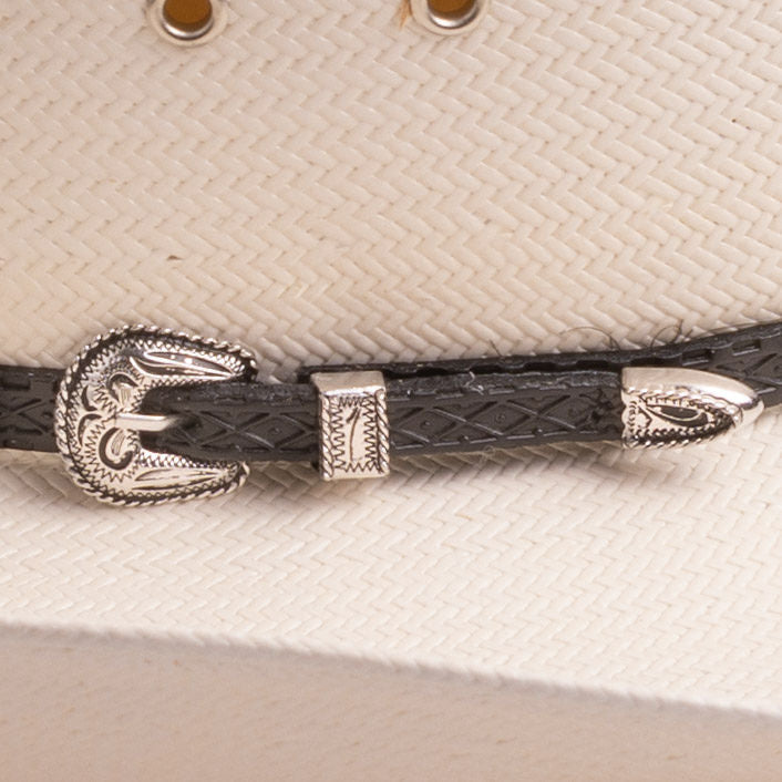 A close-up of a black braided leather hat strap with ornate silver-toned metal band, resting on a textured off-white woven surface of the hat