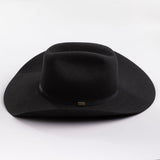 A black felt cowboy hat with a wide brim and a black band around the crown, featuring a small gold brand pin on the band, set against a clean light gray background.