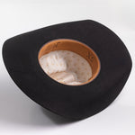 A black felt cowboy hat shown from a top-down angle, displaying its tan leather trim and cream-colored patterned interior lining